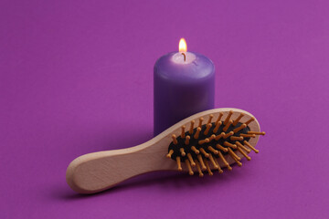 Purple burning candle and hairbrush on a purple background. Spa salon