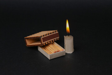 Matches With flaming candle on black background