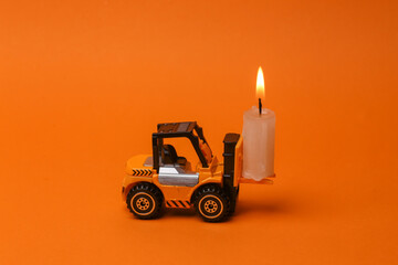 Forklift with flaming candle on orange background