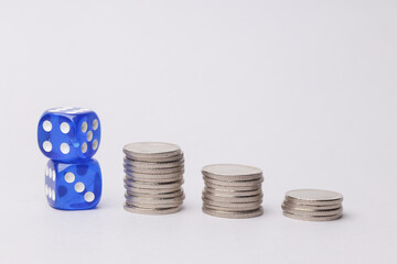 Dice with stack of coins on white background.