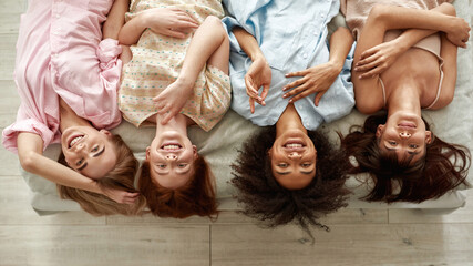 Top view of multiethnic girlfriends lying on bed