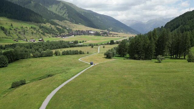 General view in mountain valley. Camera tracking blue lorry, delivering cargo on the domestic field road