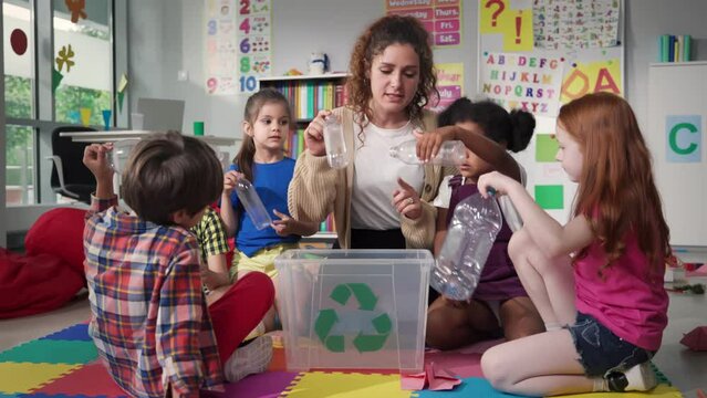 Teacher giving recycle lesson to little kids in kindergarten