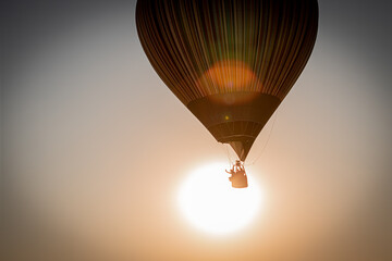 Hot air balloon flys in front of the sun at the Bristol international balloon festival, 2022 at Ashton Court Estate. 