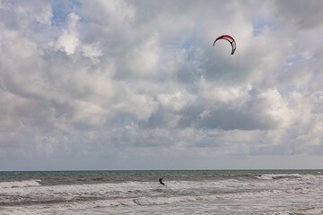 Professional kiter makes the difficult trick on a beautiful background. Kitesurfing Kiteboarding action photos man among waves quickly goes