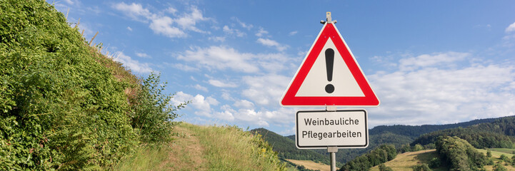 Schild am Weinberg. Achtung, Weinbauliche Pfegearbeiten. Panorama