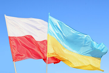 Developing waving Polish and Ukrainian flags on a blue peaceful sky, support for friendly countries...