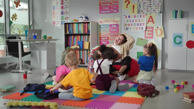 Group of elementary students exercising with teacher sitting on floor in classroom