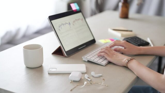 部屋でタブレットPCを操作する女性の手元
