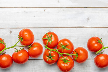 Tomato on a branch sprout on white wooden table top view flatlay. Fresh juicy ripe tomato Red Cherry fruits. Salad preparation ingredients. Empty copy space for mockup