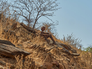 Lone man rock sculpture sitting on the side of the road