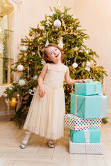 little girl with gifts by Christmas tree. tradition giving gifts