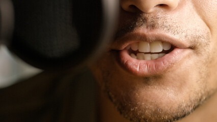 Close up on radio or podcast presenters mouth as he talks into a microphone 