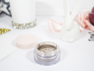 Beige loose eyeshadows for women stands on a white dressing table with a light background