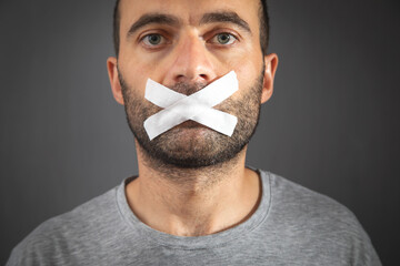 Caucasian man with tape on mouth. Censorship