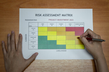 Action of a manager is using ballpoint pen to evaluate on risk assessment matrix of the Project...