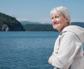Fototapeta na wymiar Portrait of happy senior caucasian woman with gray hair traveling on boat, looking into distance.