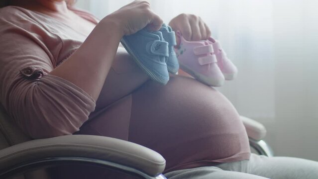 Happy pregnant woman expecting  twins. Pregnant woman feeling happy at home while taking care of her child. Pregnant woman resting alone at home strokes touches her big belly, close up. Slow motion