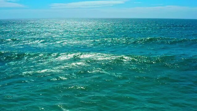 Aerial view over azure ocean with rolling waves. Top view to the ocean in summer  sunny day - closeup. Drone view of a Scenic slow motion ocean waves. Beautiful Sea blue  water with blue sky.