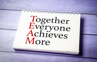 together everyone achieves more words on white notepad on wooden background