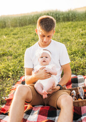  father and daughter having a picnic outdoors in the field. Playing and having fun with little baby . Happy family concept