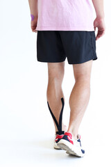 Kinesiology taping treatment with black tape on male patient injured Achilles tendon. Sports injury kinesio treatment.