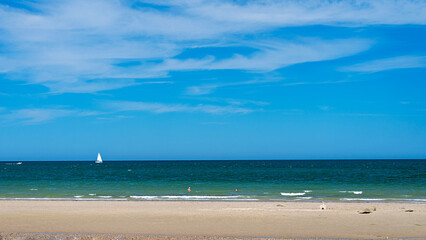 Fototapeta na wymiar Panoramic view of beach with sailing yacht in ocean sailing and sky in background