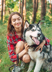 Naklejka na ściany i meble teenage girl playing and having fun with her siberian husky dog. Girl with dog in the forest