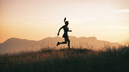 A young sportswoman runs at sunset in the hills