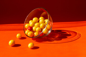 Orange background. Glass bowl with fruit. Yellow plums on an orange background. Bright light and...