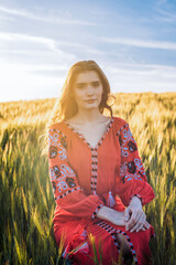 young beautiful woman wearing ukrainian traditional embroidered dress in wheat field during sunset. Stand with Ukraine