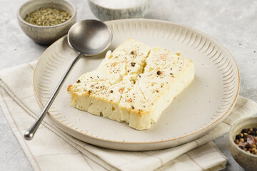 oven baked sheep cheese feta with herbs, oil and spices on round off-white plate, kitchen napkins,...