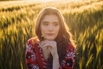 close up shot of young beautiful woman wearing ukrainian traditional embroidered dress in wheat field during sunset. Stand with Ukraine