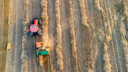 Tractor with balers in field stubble. Slanted horizontal view from drone point of view