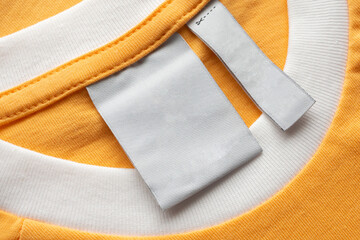 Blank white laundry care clothes label on yellow fabric texture background