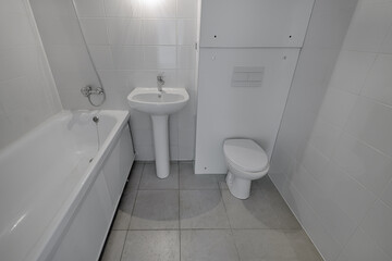 Small new bathroom with toilet, sink, bathtub. Standard, stereotype bathroom in a new apartment
