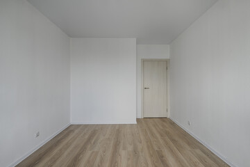 Empty room after repairs in an apartment building. Standard, stereotype fresh renovated room with wooden floor