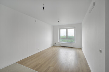 Empty room after repairs in an apartment building. Standard, stereotype fresh renovated room with wooden floor