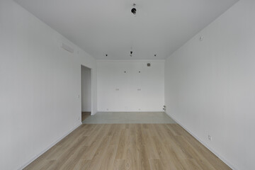 Empty room after repairs in an apartment building. Standard, stereotype fresh renovated room with wooden floor