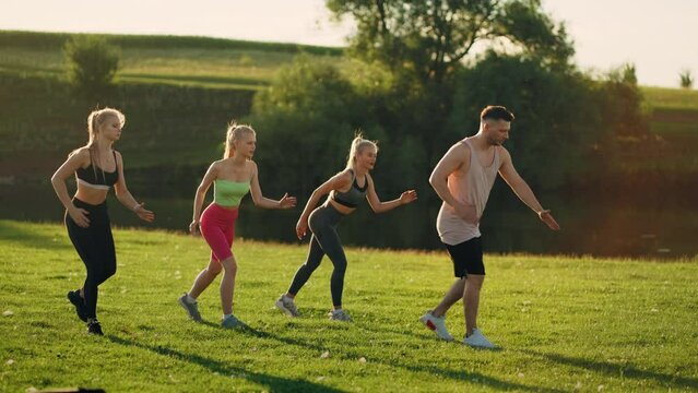 group of beautiful and sporty people are doing physical exercise in park in summer morning