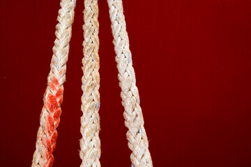 three stretched ropes on a dark red background
