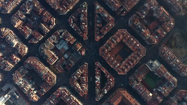 Fly above historic Avinguda Gaudi and surrounding streets and blocks of buildings. Top down shot of town development at golden hour. Barcelona, Spain