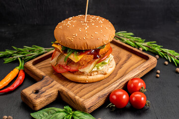 Tasty big burger with cutelete and cheese on wooden background