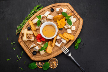 Dish of assorted tupes of cheese with honey on wooden background