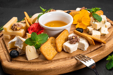Dish of assorted tupes of cheese with honey on wooden background