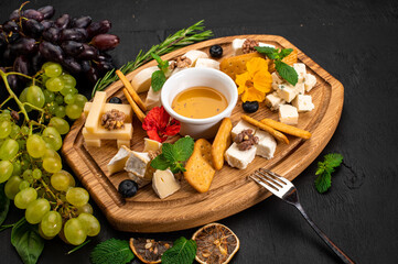 Dish of assorted tupes of cheese with honey on wooden background