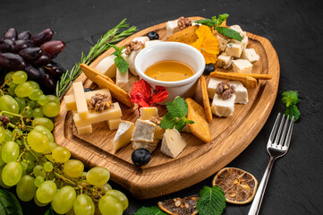 Dish of assorted tupes of cheese with honey on wooden background