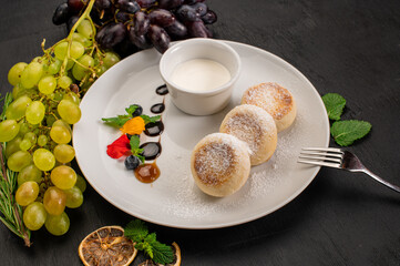 Dish of cheese pancekes with syrup on wooden background