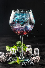 Colored blue and red cocktail with blueberry and ice on black background - 524634635
