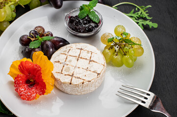 Dish with cheese camambert with fruits on wooden background